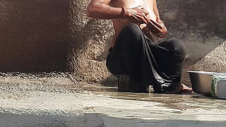 Indian sister-in-law is bathing in the open courtyard of the house, putting a finger in her burrow and rubbing the body, sister-in-law is washing the bathroom.