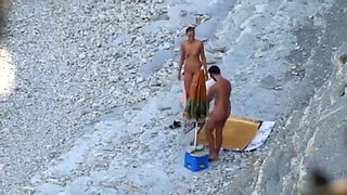 Couple strips and blows on the beach