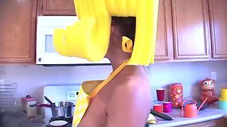 A huge-chested woman in a yellow peruke uses a fake penis
