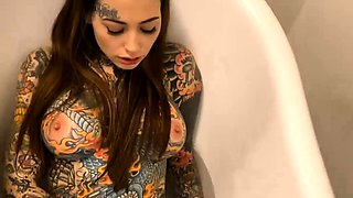Buxom tattooed brunette making herself cum in the bathtub
