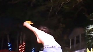 Three topless girls ride a mechanical bull in public